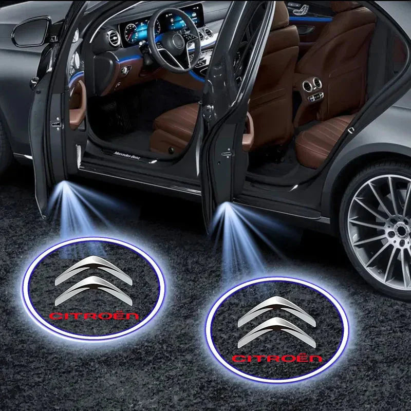 Auto con portiere aperte, proiettori logo Citroën illuminati sul pavimento. Interni di lusso, volante e sedili visibili. Accessori auto eleganti.