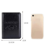 Custodia passaporto in pelle nera con incisione, dimensioni 10.5x14 cm, accanto a uno smartphone dorato. Accessorio viaggio elegante e pratico.