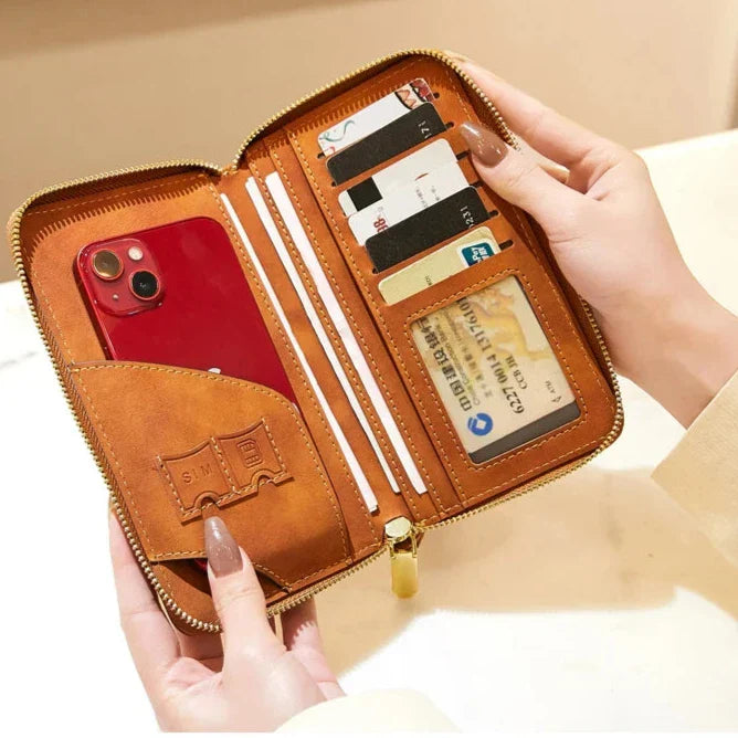 Portafoglio in pelle marrone aperto con zip, contenente uno smartphone rosso, carte di credito e documenti. Design elegante e funzionale per organizzazione.
