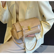 Borsa a tracolla beige in pelle, design elegante con chiusura dorata, indossata su giacca bianca. Accessorio moda donna, stile sofisticato.