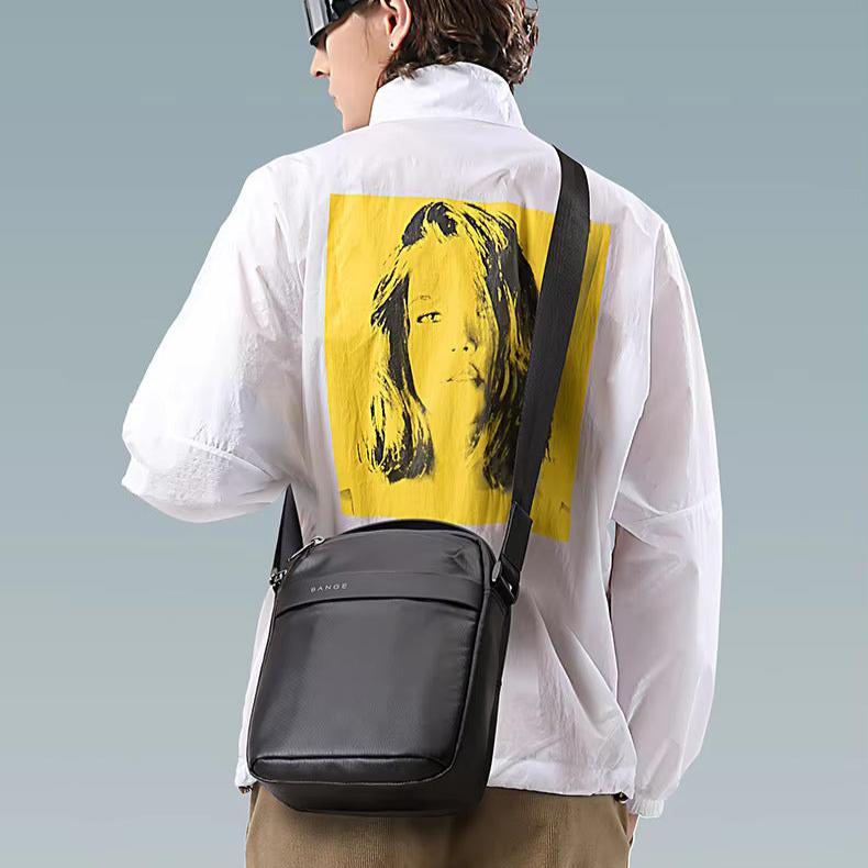 Giacca bianca con stampa gialla, borsa a tracolla nera in pelle, moda uomo, stile casual, accessori eleganti, abbigliamento moderno.