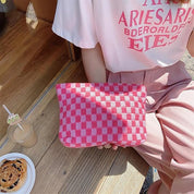 Donna con borsa a scacchi rosa e bianca, seduta accanto a bevanda e dolce. Moda estiva, accessori femminili, stile casual chic.