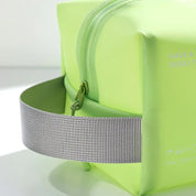 Astuccio da viaggio verde lime con cerniera e manico grigio, design moderno e compatto, ideale per cosmetici e accessori.