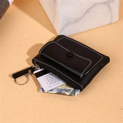 Portafoglio nero in pelle con cuciture bianche, tasca con zip, portachiavi e scomparti per carte e contanti. Accessorio elegante e funzionale.