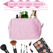 Astuccio trucco a righe rosa con ampio spazio, contenente cosmetici e pennelli. Ideale per organizzare il make-up. Accessorio viaggio essenziale.