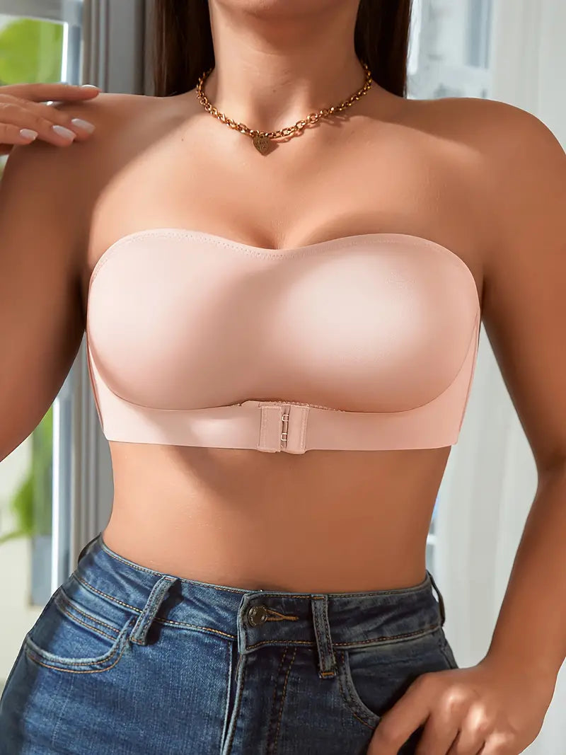 Reggiseno senza spalline color nude, design liscio, chiusura frontale, indossato con jeans. Intimo femminile elegante e confortevole.