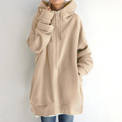 Felpa oversize beige con cappuccio, zip frontale e tasche, indossata da una persona. Stile casual, ideale per moda autunnale e invernale.