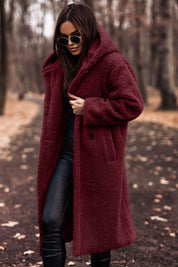 Donna con cappotto teddy borg rosso, occhiali da sole, pantaloni neri in pelle, in un parco autunnale. Moda invernale, stile casual chic.
