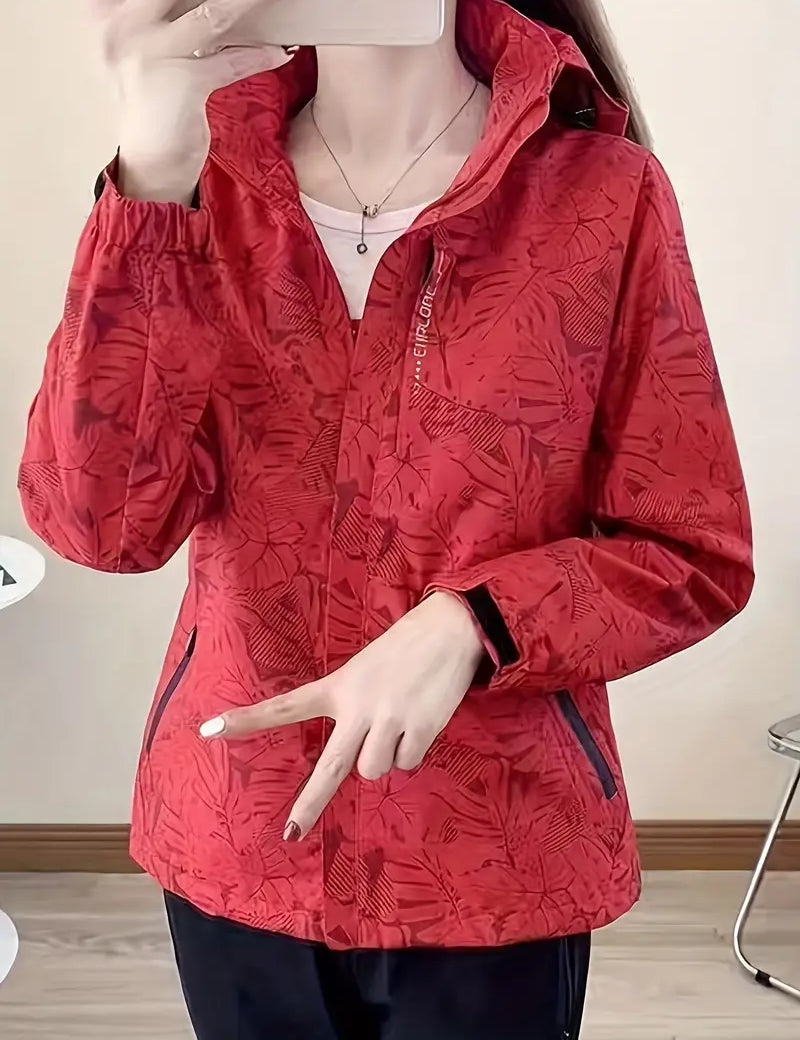 Giacca a vento rossa con motivo floreale, chiusura zip, tasche laterali, indossata da una persona. Ideale per attività all'aperto e sport.