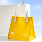 Borsa tote gialla trasparente con manici bianchi, design moderno, ideale per shopping e viaggi. Stile elegante e pratico per ogni occasione.