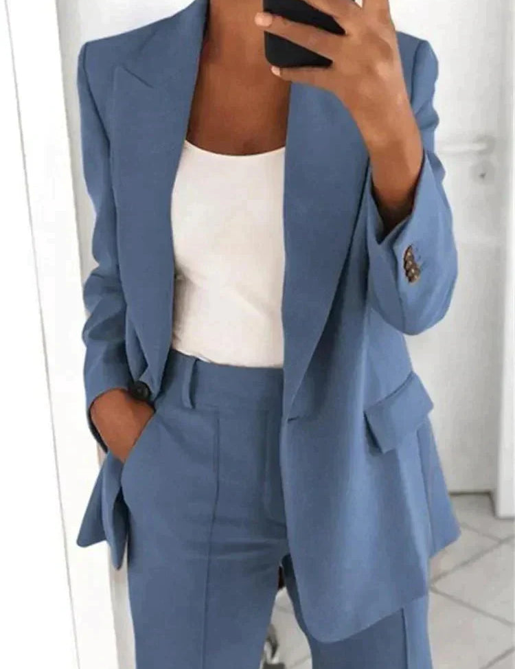 Completo donna elegante blu, giacca e pantaloni abbinati, indossato con top bianco. Moda femminile, abbigliamento formale, stile business casual.