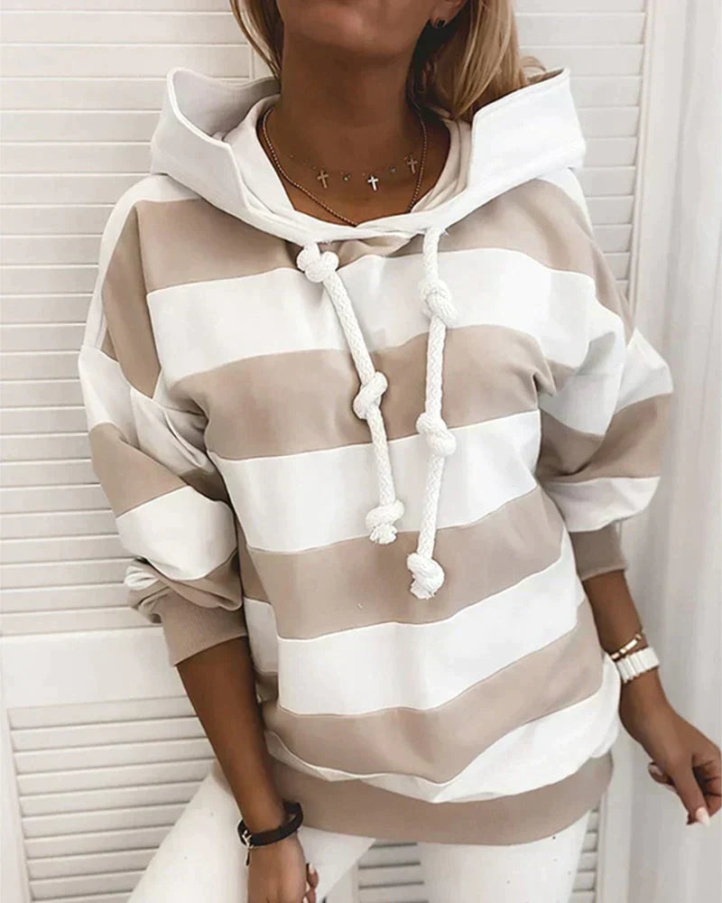 Felpa a righe bianche e beige con cappuccio e lacci spessi, indossata da una donna. Moda casual, abbigliamento autunnale, stile confortevole.