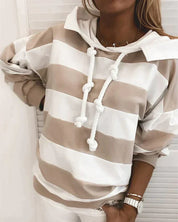 Felpa a righe beige e bianche con cappuccio e lacci, indossata da una donna. Moda casual, abbigliamento autunnale, stile confortevole.