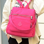 Zaino rosa vivace con tasche multiple e cerniere, indossato da una persona. Design moderno, ideale per scuola o viaggio. Accessorio moda trendy.