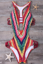 Costume da bagno intero multicolore a righe, design cut-out, su sfondo in legno con stelle marine. Moda mare donna, estate, tendenze 2023.