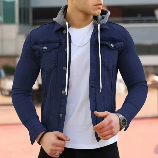 Giacca di jeans blu scuro da uomo con cappuccio grigio, indossata sopra una maglietta bianca. Stile casual, moda maschile, abbigliamento urbano.