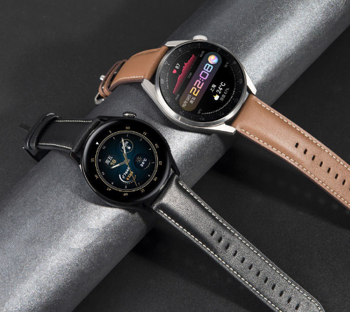 Due smartwatch eleganti con cinturini in pelle marrone e nero, display digitale a colori, su sfondo grigio. Tecnologia indossabile moderna.