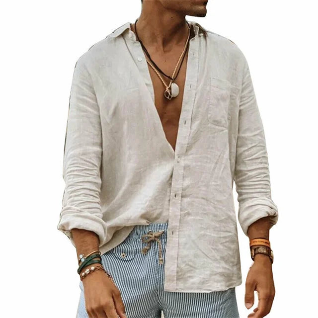 Camicia uomo in lino bianco, maniche lunghe, abbinata a pantaloni a righe blu. Stile casual estivo, accessori con bracciali e collane.