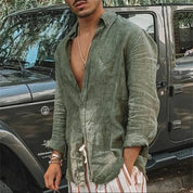 Camicia di lino verde da uomo, stile casual, abbinata a pantaloni a righe, davanti a un SUV grigio. Look estivo elegante e rilassato.