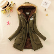 Giacca invernale verde con cappuccio in pelliccia sintetica, chiusura a zip, tasche frontali e dettagli decorativi. Elegante e calda per l'inverno.