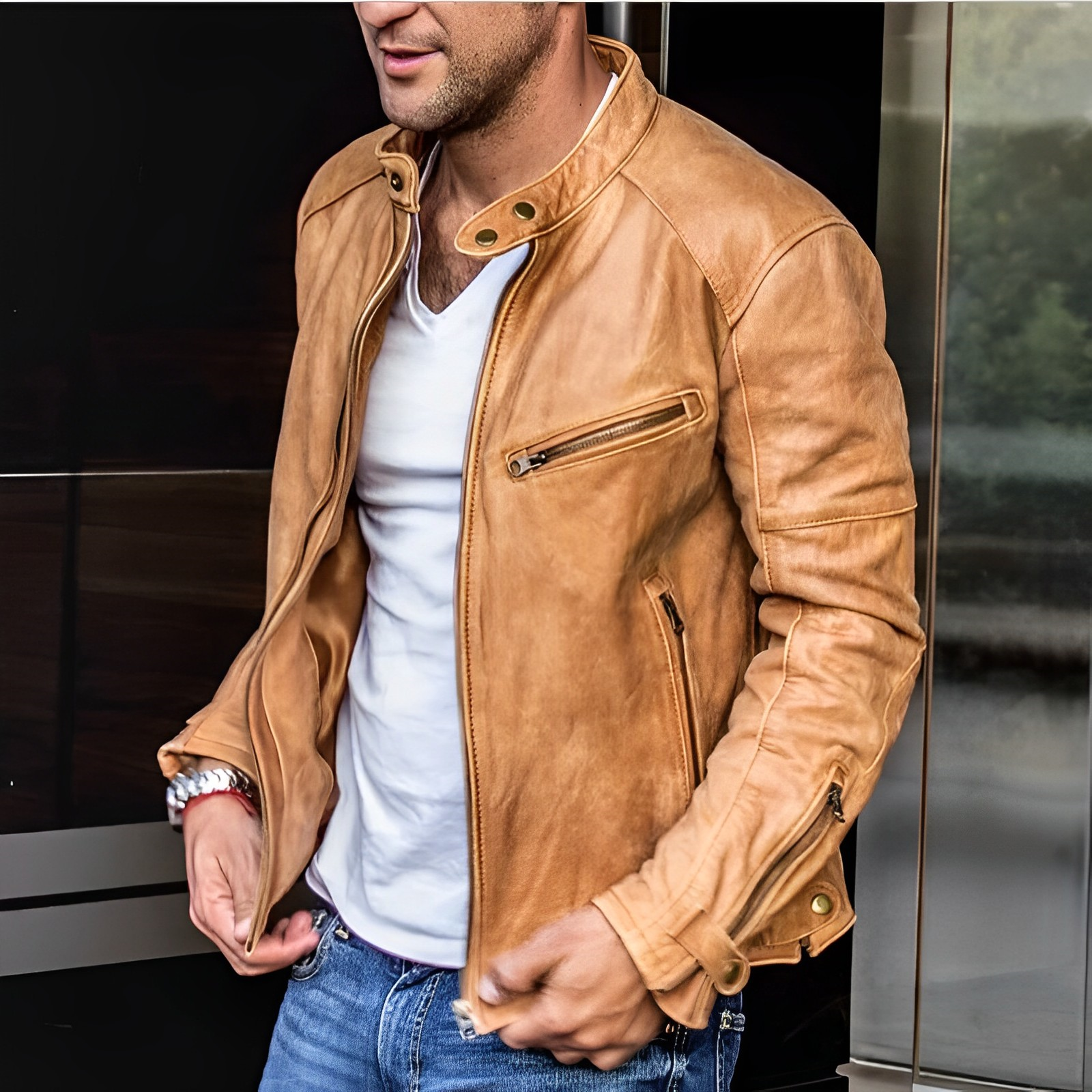 Giacca in pelle marrone da uomo, stile casual, con zip e tasche, abbinata a jeans e maglietta bianca. Moda maschile autunnale.