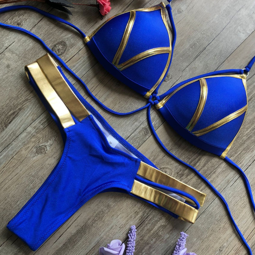 Bikini donna blu e oro su sfondo legno, design moderno, due pezzi, costume da bagno estivo, moda mare, abbigliamento da spiaggia elegante.