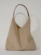 Borsa a spalla in pelle scamosciata beige con manico marrone, design minimalista. Accessorio moda elegante e versatile per ogni occasione.