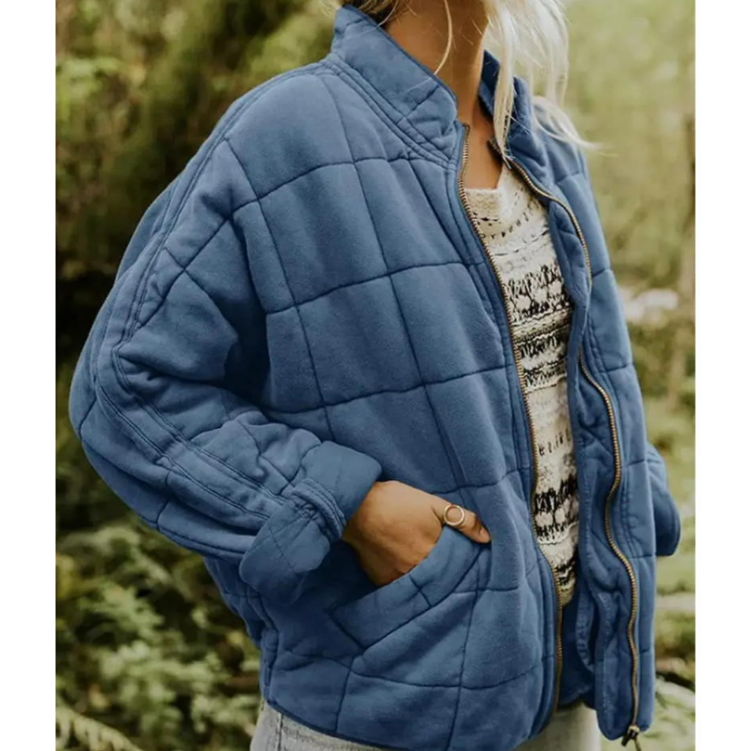 Giacca trapuntata blu donna, stile casual, con zip frontale e tasche, indossata su maglia a fantasia, moda autunno inverno, abbigliamento outdoor.
