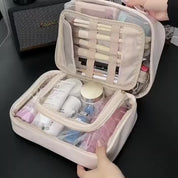 Borsa da trucco beige aperta con pennelli, creme e cosmetici organizzati. Ideale per viaggi, beauty case compatto e spazioso.