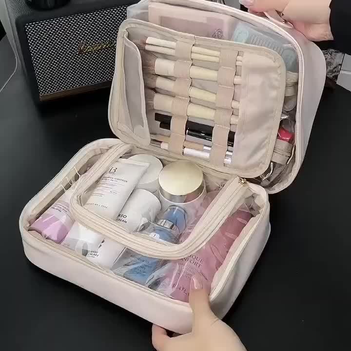 Borsa da trucco beige aperta con pennelli, creme e cosmetici organizzati. Ideale per viaggi, beauty case compatto e spazioso.