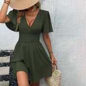 Donna con abito verde oliva estivo, scollo a V, maniche corte, cappello di paglia, borsa intrecciata. Moda estiva elegante e casual.