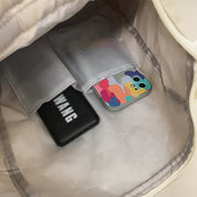Zaino aperto con tasche interne contenenti un power bank nero e uno smartphone con cover colorata. Accessori tecnologici portatili.