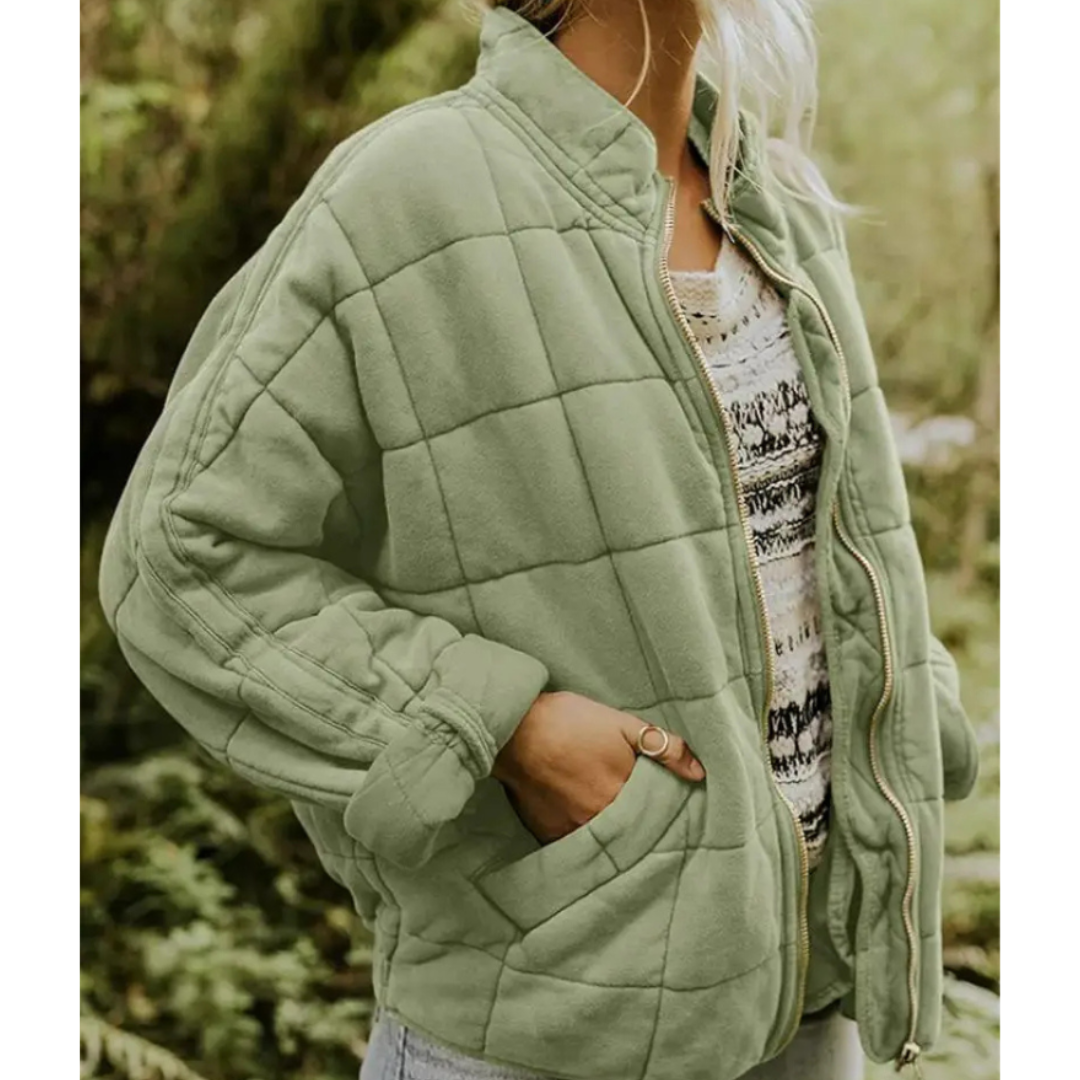 Giacca trapuntata verde donna, stile casual, con zip e tasche, indossata su maglia a fantasia. Moda autunnale, abbigliamento outdoor.