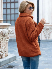 Giacca in pelliccia sintetica marrone donna, stile casual, indossata con jeans, occhiali da sole, sfondo urbano. Moda autunno inverno.