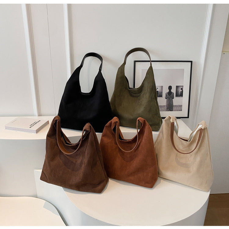 Cinque borse a spalla in pelle scamosciata in vari colori (nero, verde, marrone, beige) su sfondo bianco, design elegante e moderno.