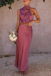 Abito da cerimonia elegante in raso rosa, top senza maniche e gonna lunga, bouquet di fiori bianchi, moda donna, abbigliamento formale.