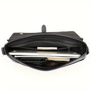 Borsa a tracolla in pelle nera aperta, con laptop, portafoglio e libri all'interno. Elegante e pratica per lavoro e studio.