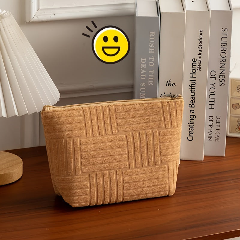 Pochette beige in tessuto trapuntato su tavolo in legno, accanto a libri e lampada. Design elegante, ideale per accessori moda.