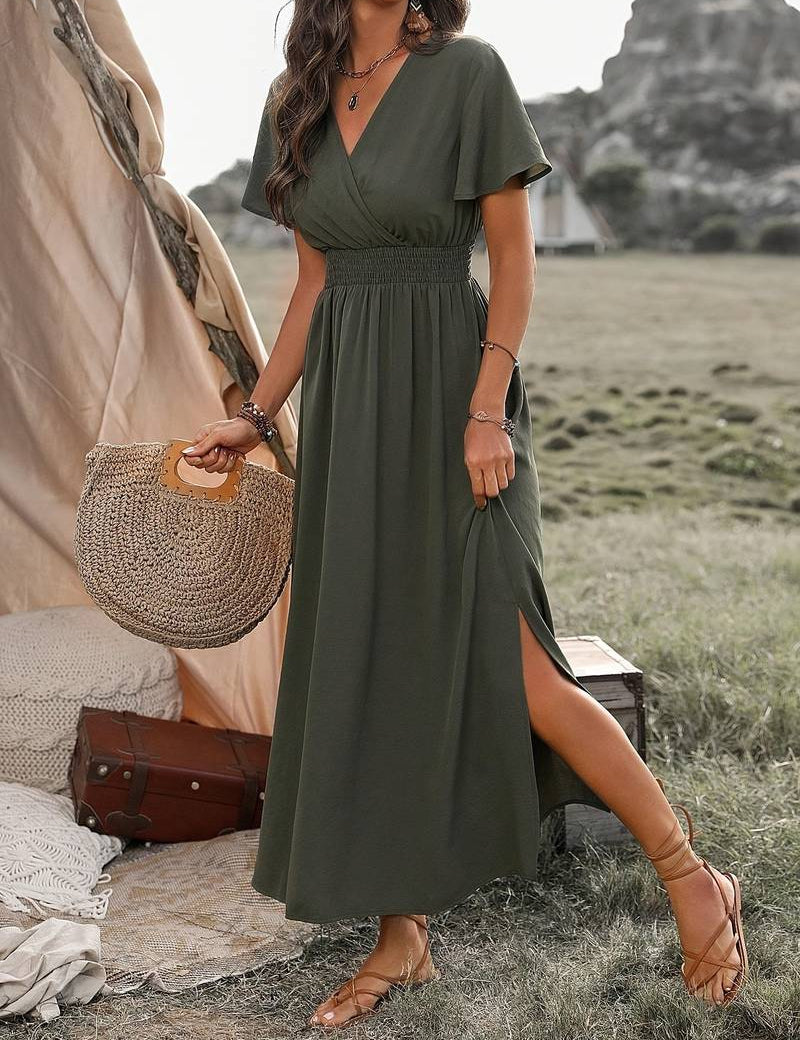 Donna con abito lungo verde oliva, borsa di paglia, sandali, in un ambiente naturale. Moda estiva, abbigliamento casual elegante.