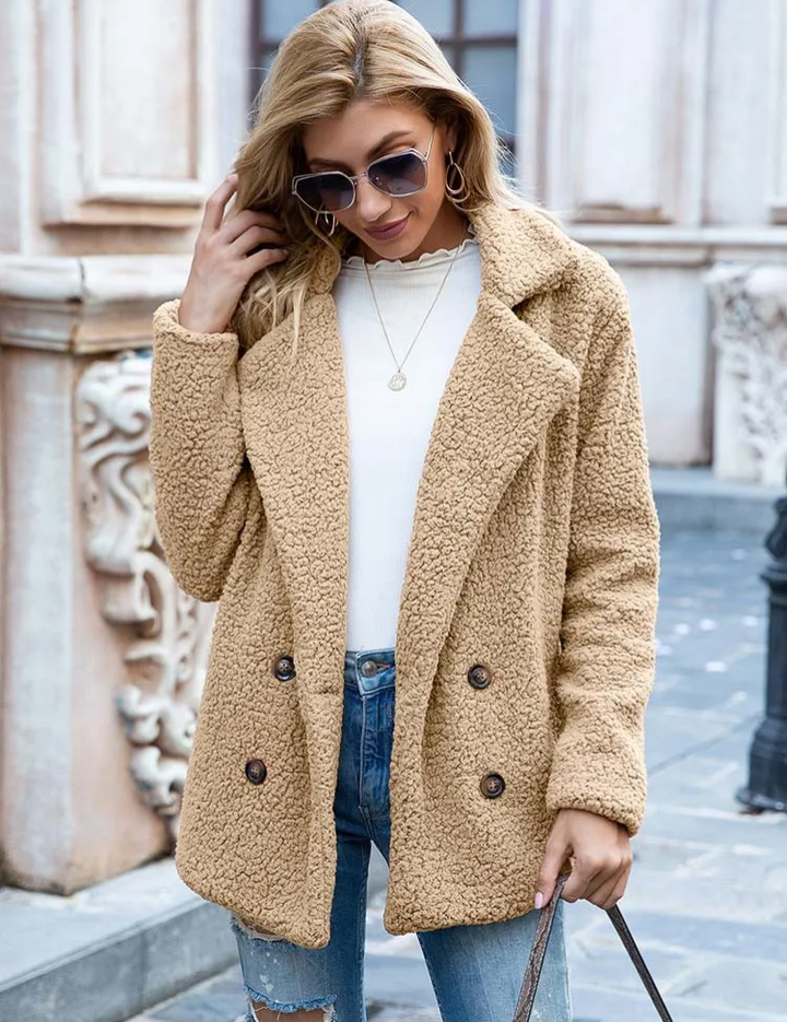 Cappotto donna in pelliccia sintetica beige, doppio petto, indossato con jeans strappati e maglia bianca. Stile casual autunnale.