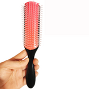Spazzola per capelli con setole rosa e manico nero, ideale per districare e lisciare. Accessorio essenziale per la cura dei capelli.