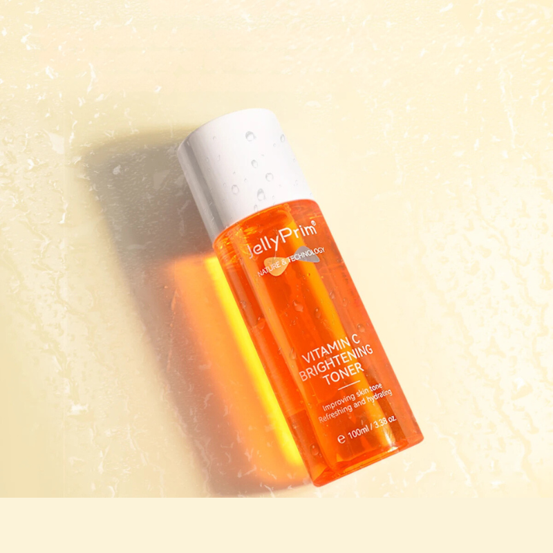 Tonico illuminante alla vitamina C JellyPrim, flacone arancione da 100ml su sfondo chiaro, skincare viso, miglioramento luminosità, idratazione pelle.