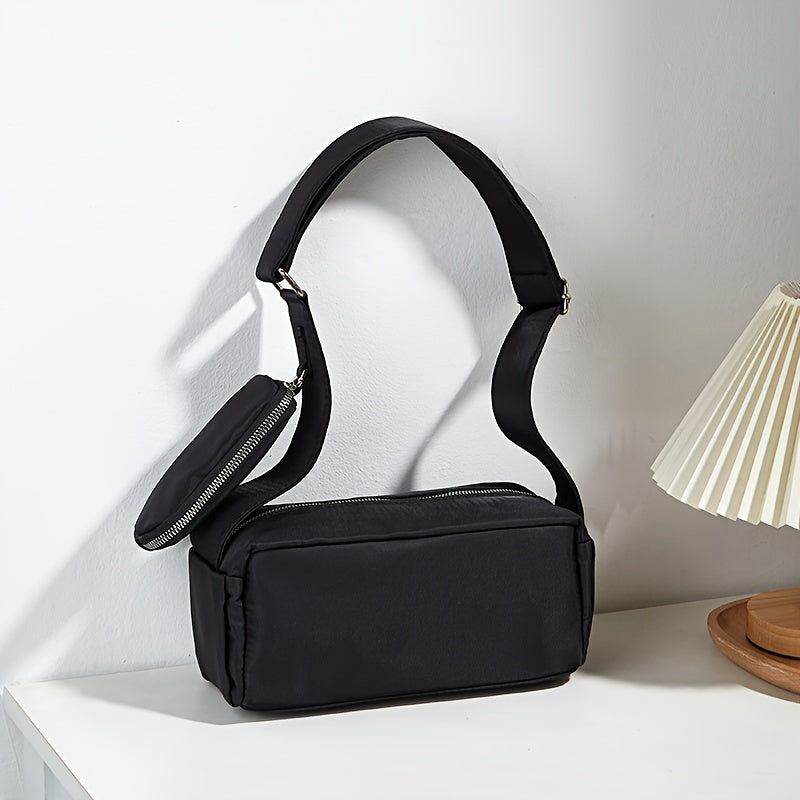 Borsa a tracolla nera elegante su tavolo bianco, design minimalista, con tasca con zip, perfetta per moda donna, accessori versatili e moderni.