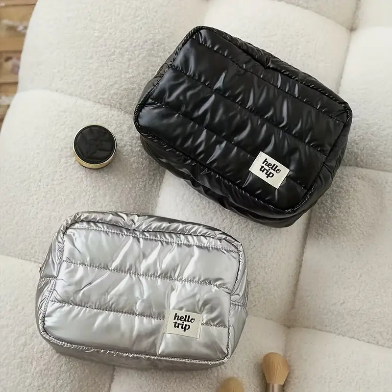 Due pochette trapuntate, una nera e una argento, su un divano bianco. Accessori moda eleganti, ideali per viaggi e organizzazione.