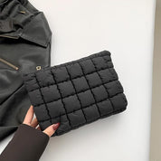 Borsa a mano trapuntata nera su sfondo bianco, accanto a giacca in pelle. Design elegante, moda donna, accessorio chic, stile contemporaneo.