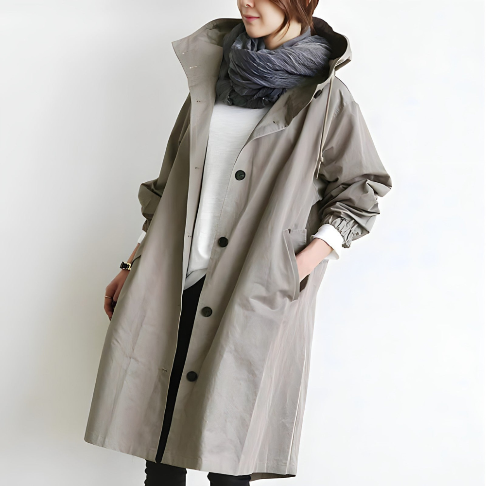 Donna con cappotto beige lungo, sciarpa grigia, camicia bianca e pantaloni neri. Moda autunnale, abbigliamento casual elegante.