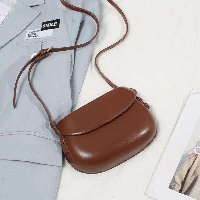 Borsa a tracolla in pelle marrone su giacca grigia, design elegante e minimalista, accessorio moda donna, perfetto per look casual e formali.