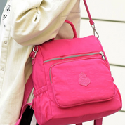 Zaino rosa acceso con tasca frontale e cerniera, indossato su spalla. Design moderno, ideale per scuola o viaggio. Accessorio moda trendy.