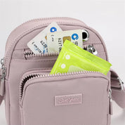 Zaino rosa compatto con tasche multiple, contenente carte di credito, smartphone e salviettine. Accessorio moda pratico e versatile per donna.