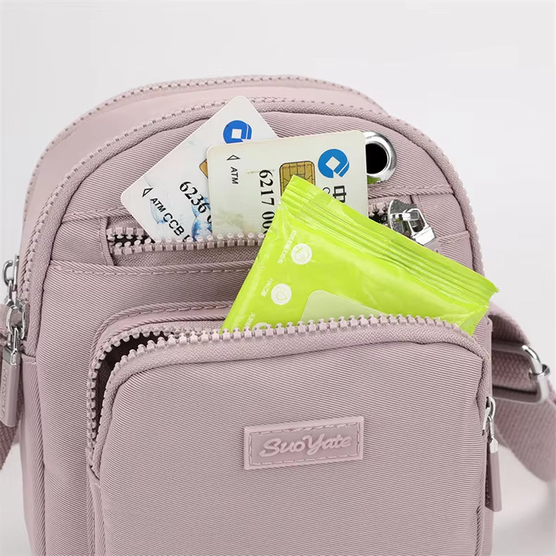 Zaino rosa compatto con tasche multiple, contenente carte di credito, smartphone e salviettine. Accessorio moda pratico e versatile per donna.